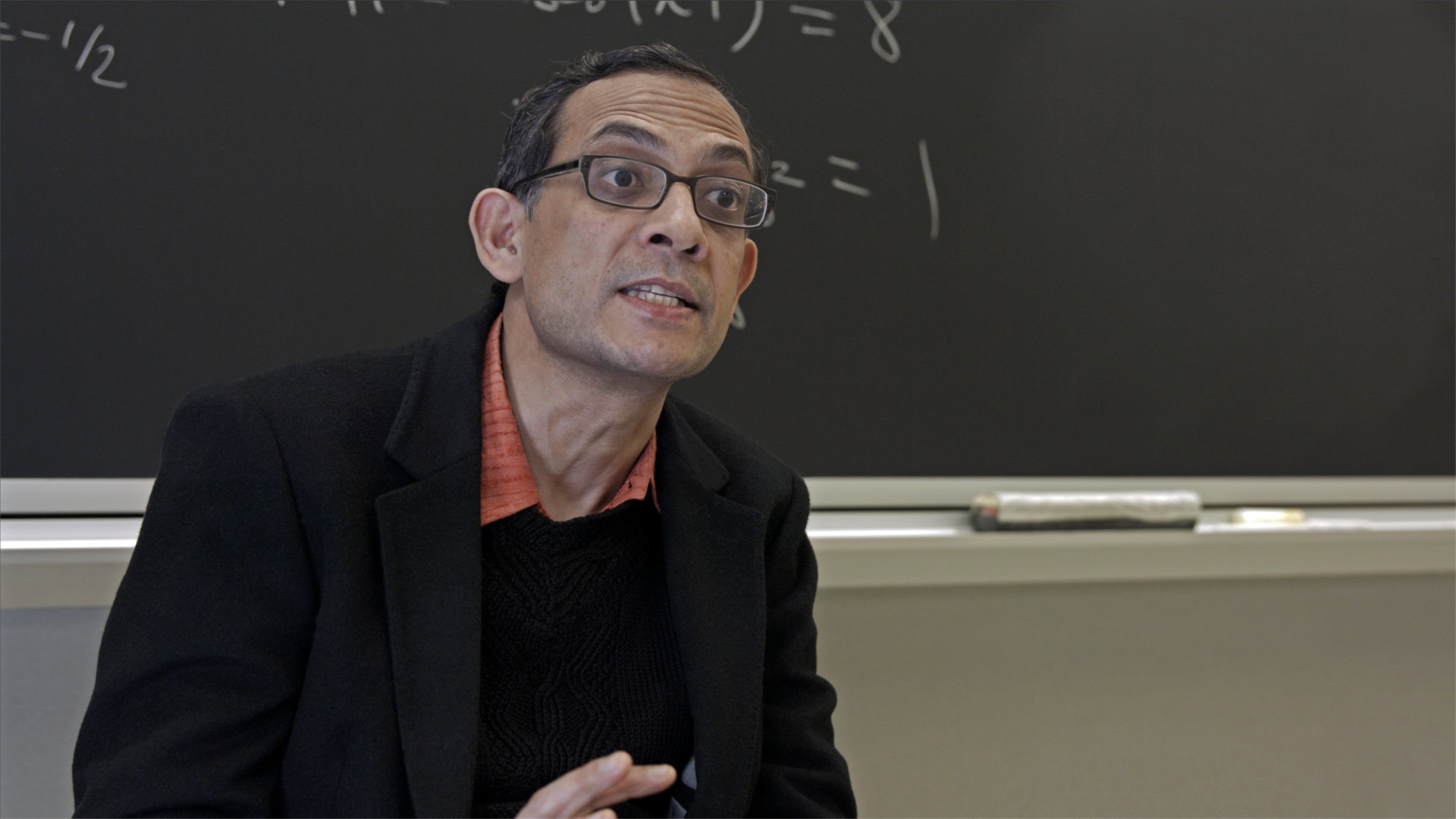 Abhijit Banerjee Disparity Film Still, Abhijit Banerjee in front of blackboard