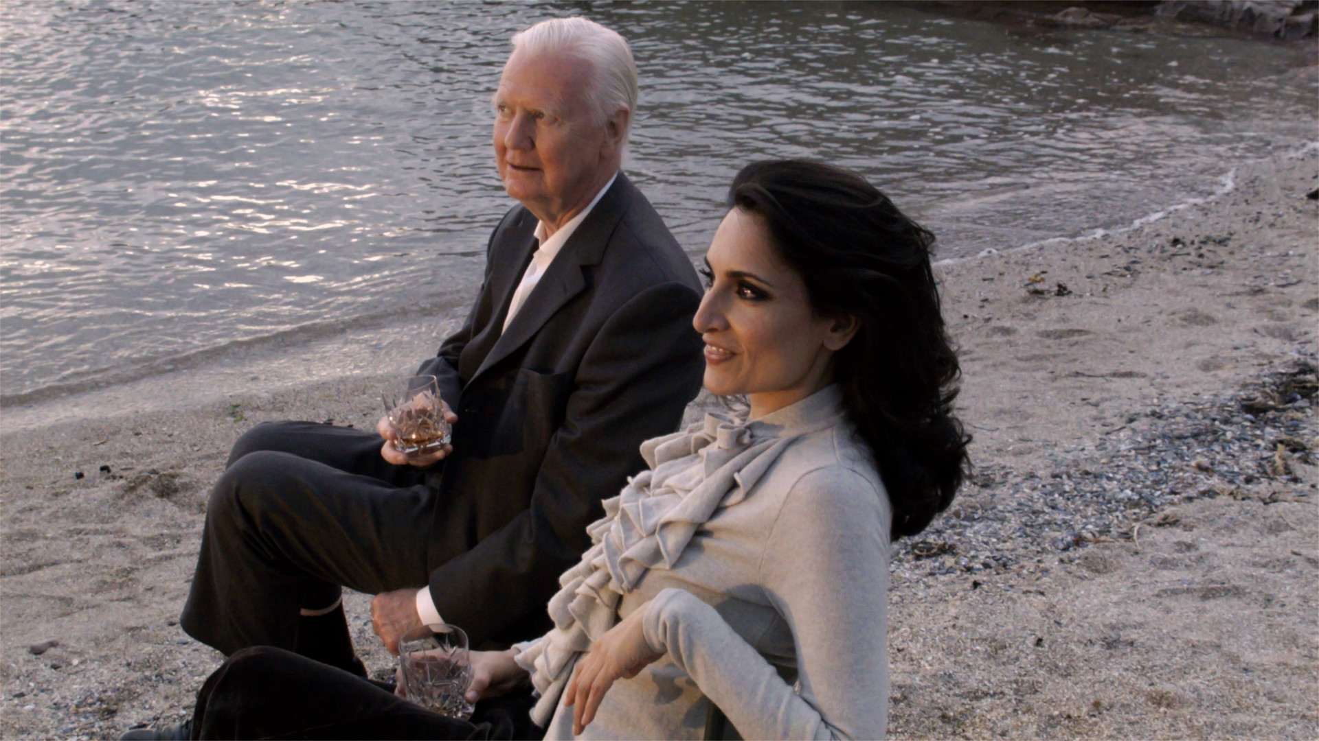 Renu Mehta and Sir James Mirrlees Disparity Film Still, Renu Mehta and Sir James Mirrlees sitting on beach