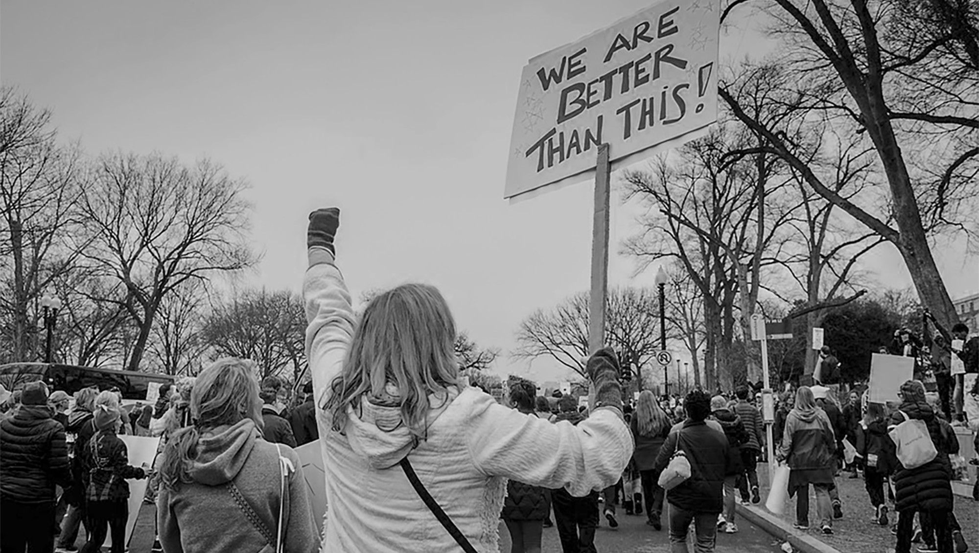 Protestor holding sign saying "we are better than this"